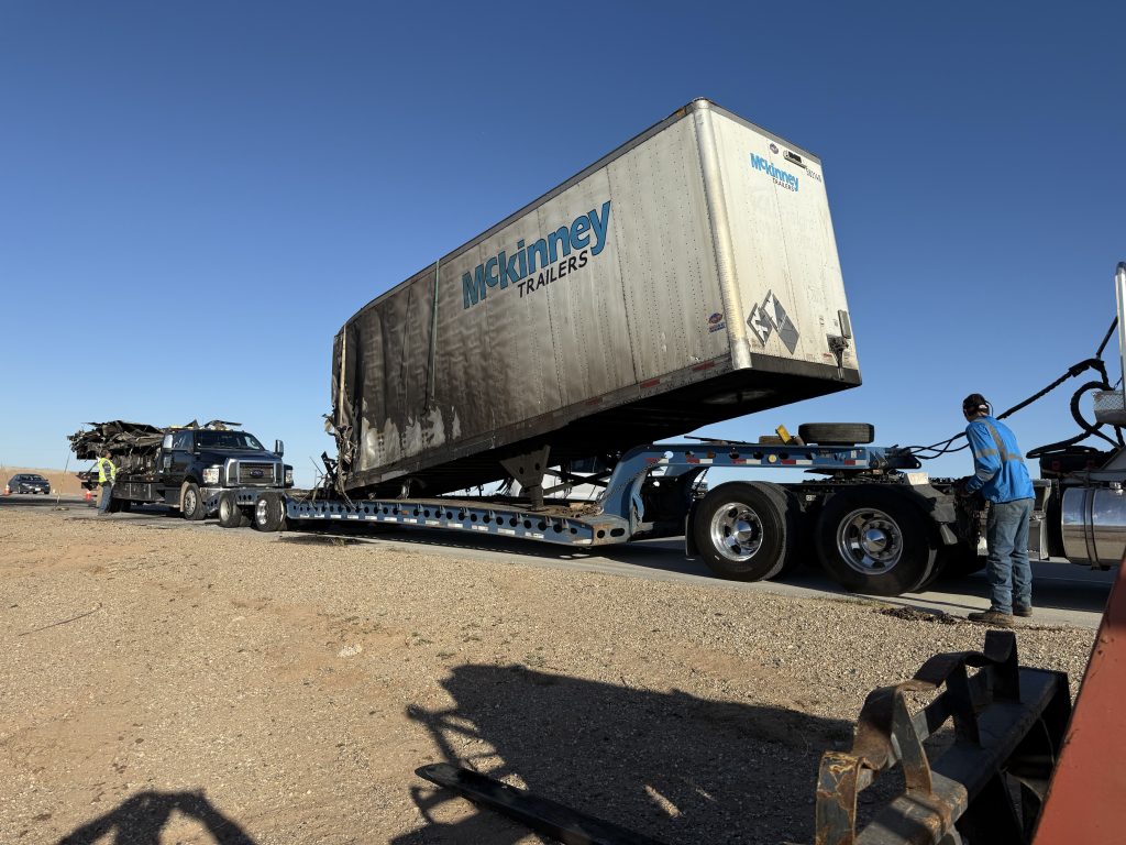 A heavy-duty tow truck transports a burnt commercial trailer in Jacumba Hot Springs, CA.
